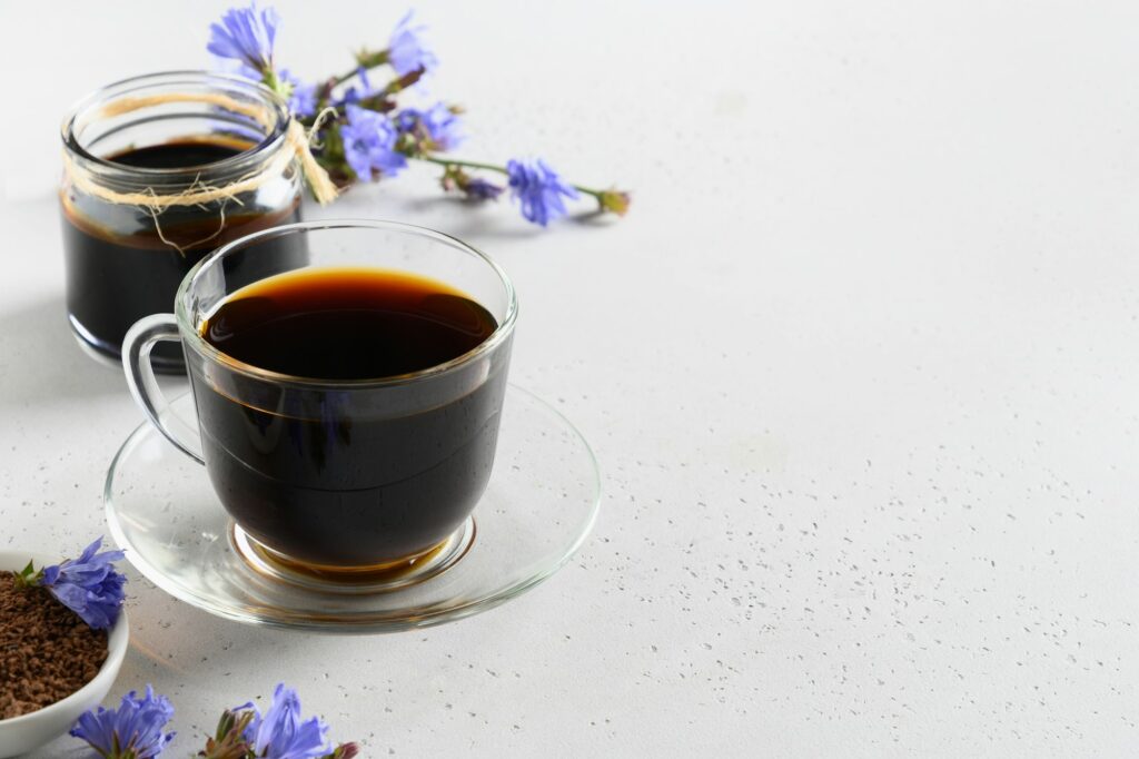 Chicory Root Coffee in glasses and fresh flowers. Health Benefits.