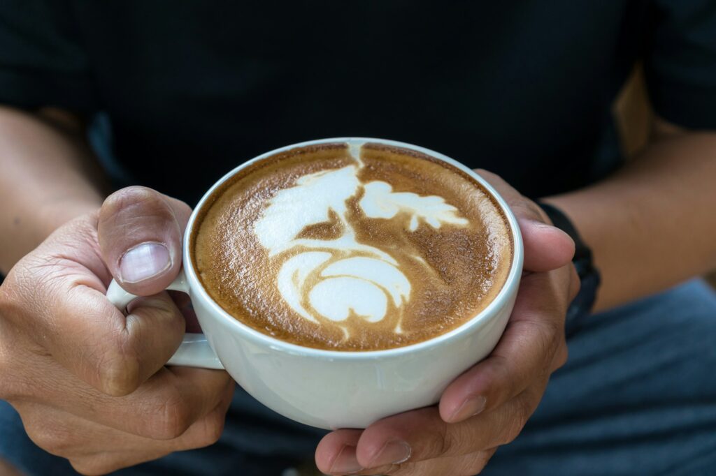 Closeup man hand holding the cup of coffee with latte art, art and drink concept