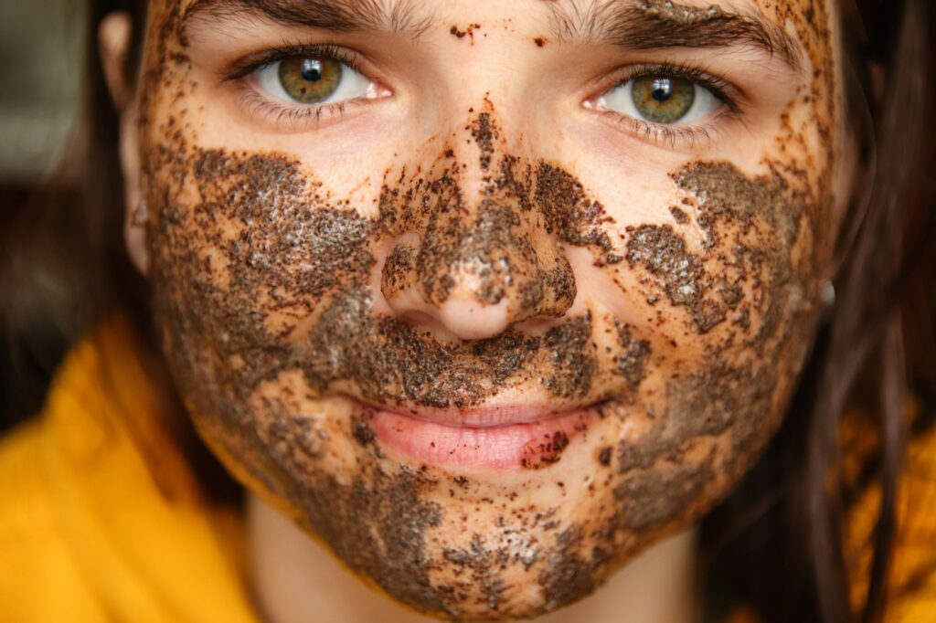 Facial mask application with coffee-based skincare. Young woman with coffee mask on face. DIY coffee