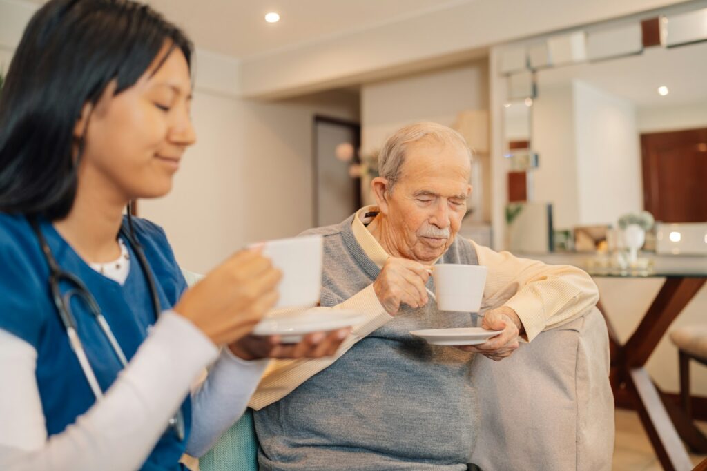 Home nurse and old man drinking decaf coffee together