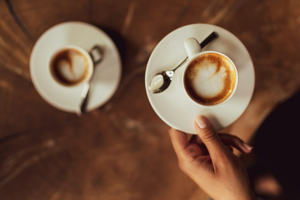 The woman is holding her espresso macchiato