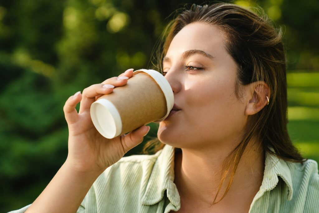 Woman drinking hot beverage drink tea coffee decaf sugar free with lactose free milk in paper cup