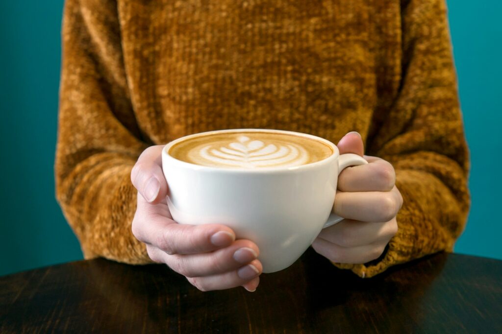 Woman headless and hands with latte.